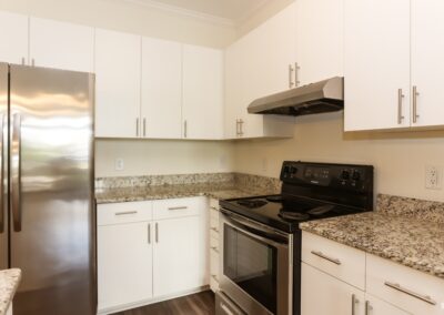 A kitchen with white granite countertops, white cabinets, and stainless steel appliances.